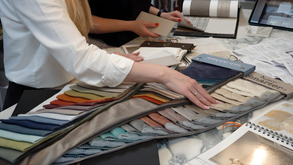 Reviewing colourful fabric and textile samples across a studio table, selecting materials for an interior design project in Galway, Ireland.