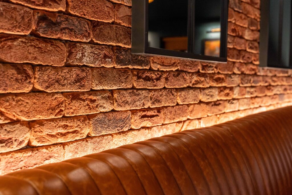 46-Ther Earl Inn (1) Leather banquette seating detail in The Earl Inn restaurant interior with textured brick wall and hospitality upholstery sourced by The Design Barn.